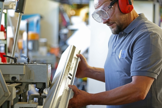 Ein Mitarbeiter von Metallbau SIEG inspiziert den Rahmen, welchen er soeben gefräst hat